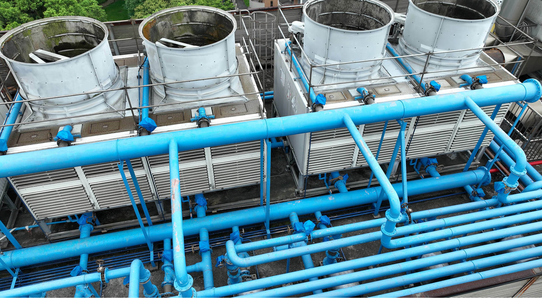 Aerial view of industrial cooling towers and blue fluid piping systems at a data center facility